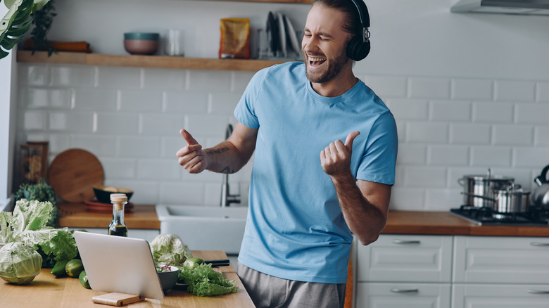 A young man enjoying music in the kitchen