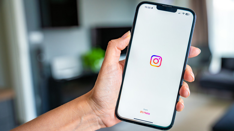 A person holding an iPhone with the Instagram app running on it