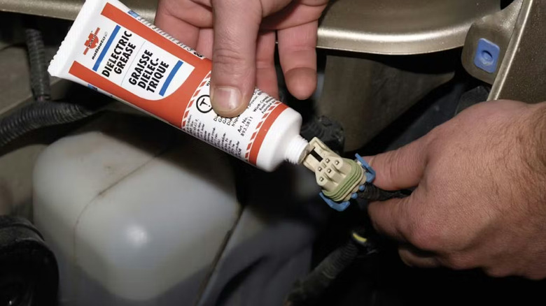 A person applying dielectric grease to an electrical connector