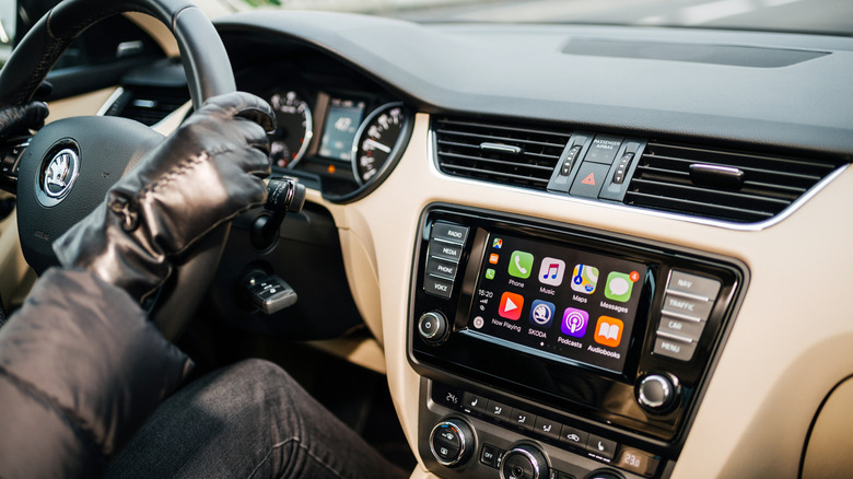 Close up of a person driving Skoda Octavia car wearing leather gloves with large dashboard display computer featuring CarPlay