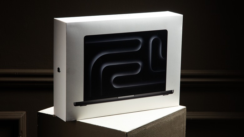 A MacBook Pro box sitting on a pedestal in a dark room