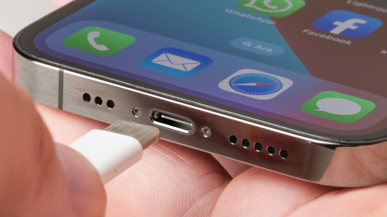 An iPhone user is plugging a USB-C cable into the charger port