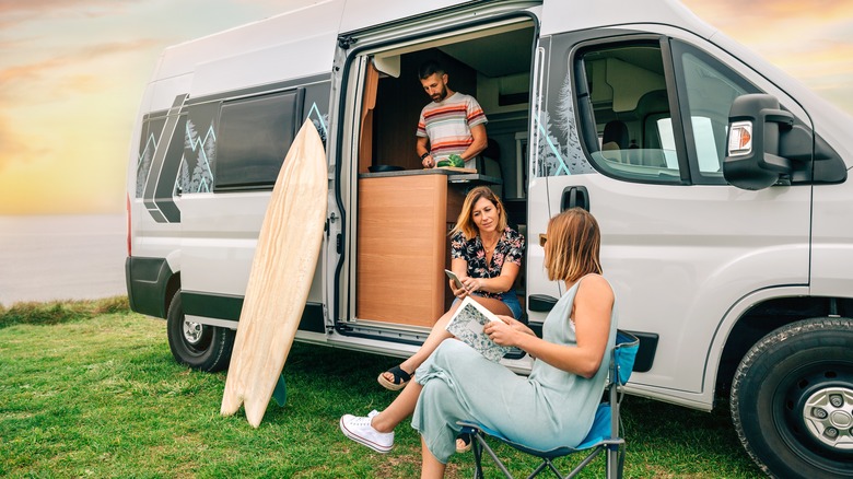 friends using camper van by the water