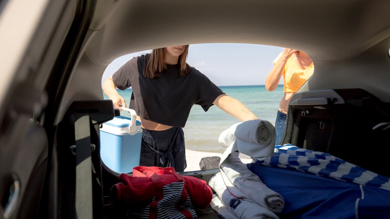 Woman packing beach items into the trunk of a car