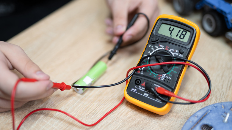 A person testing voltage on battery with multimeter