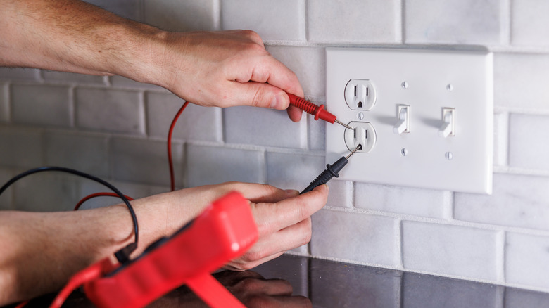 A person testing an outlet with multimeter