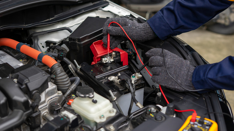 A mechanic testing a car battery with multimeter