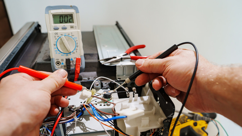 A person using a multimeter on an appliance