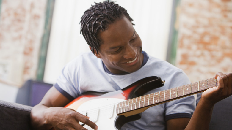 Man playing guitar on couch