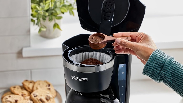 Hand adding coffee grounds to Black+Decker coffee maker