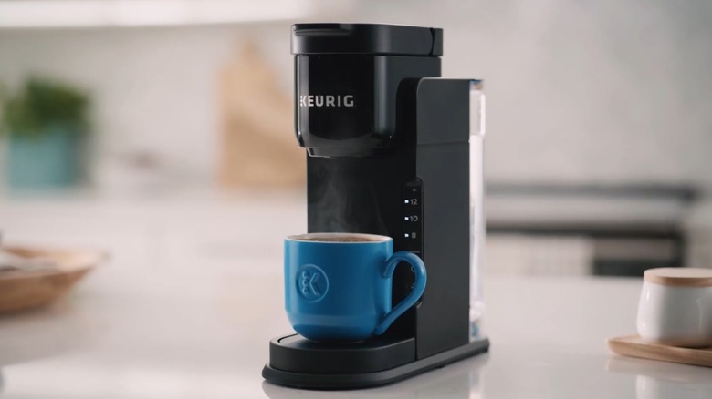 A small, black Keurig K-Express with a blue cup resting below it.