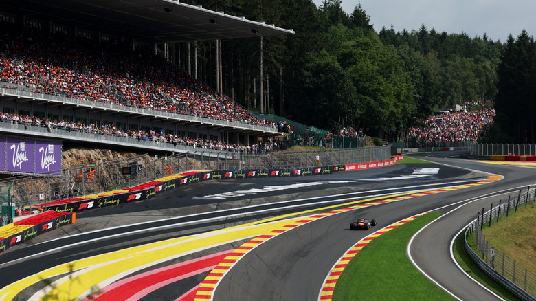 A wide shot of a McLaren F1 car driving up Eau Rouge/Raidillon at Spa-Franchorchamps