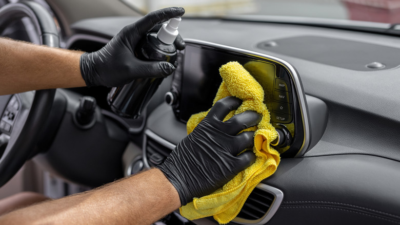 A professional cleaning the interior of the vehicle with a spray and microfiber cloth