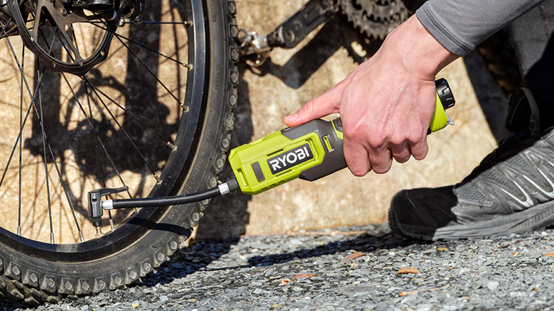 A man pumping up a bike tire with a Ryobi inflator