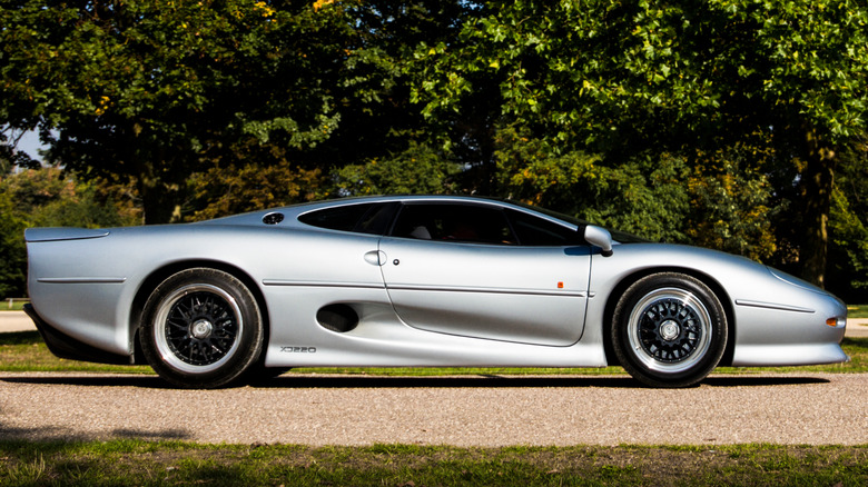 A silver Jaguar XJ220 on a country road.
