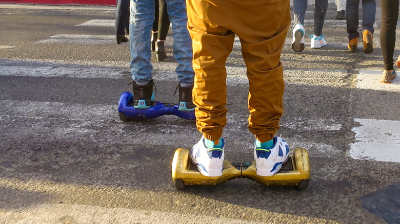 Several people riding hoverboards in public