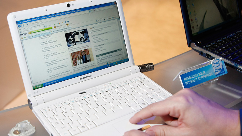 A person using a small netbook on a glass display