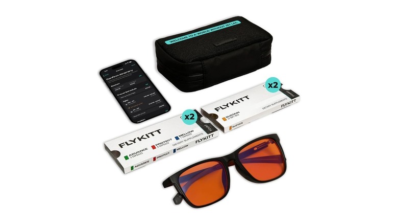 The Flykitt kit, which includes sunglasses, four boxes of supplements, and a phone with an app open.