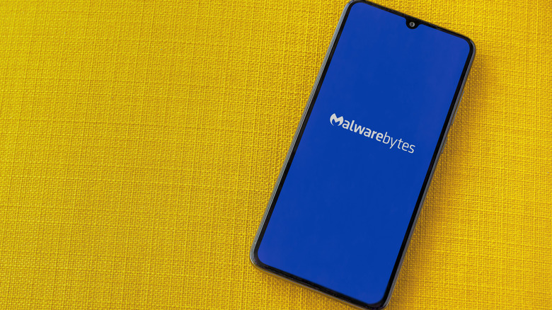 Malwarebytes antivirus app logo displayed on a smartphone with a yellow background