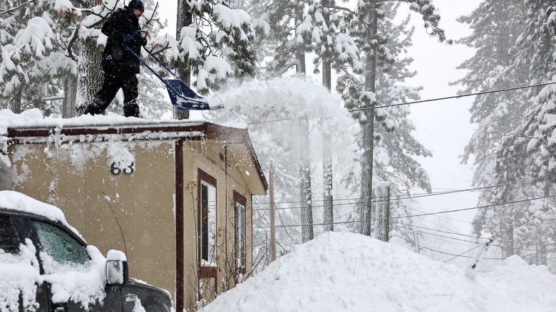 Person removing snow from a residential rooftop