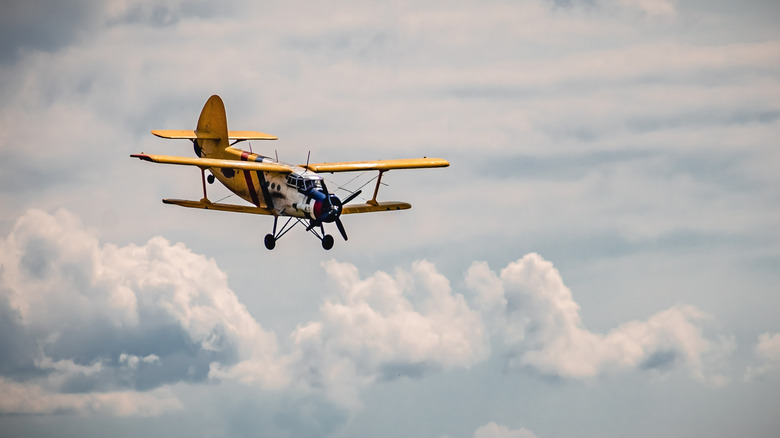 A small yellow propeller plane in the sky.