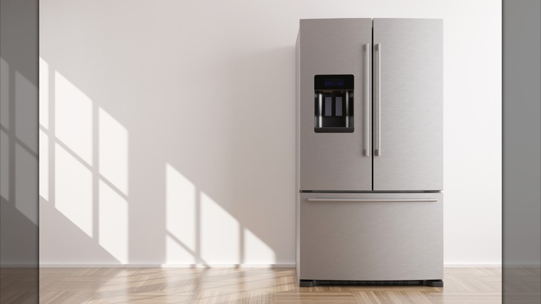 A kitchen with a refrigerator in front of white walls