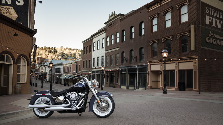 Harley-Davidson Softail Deluxe motorcycle parked on a brick-paved street in a historic downtown area