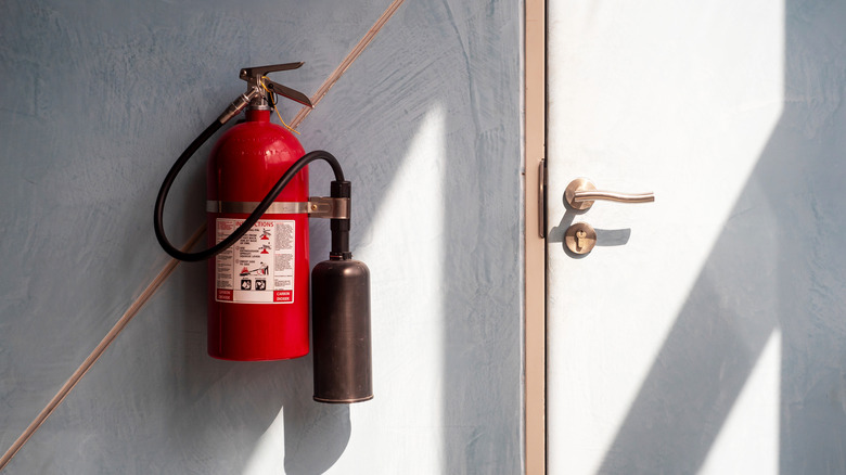 A fire extinguisher hanging from a wall beside a door