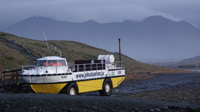 An Amphibious wheeled car located in iceland, right to left view, painted a vibrant yellow and white.