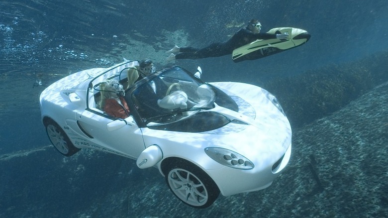 Rinspeed sQuba underwater car driving below the ocean surface with scuba divers alongside, showcasing submersible electric vehicle technology.