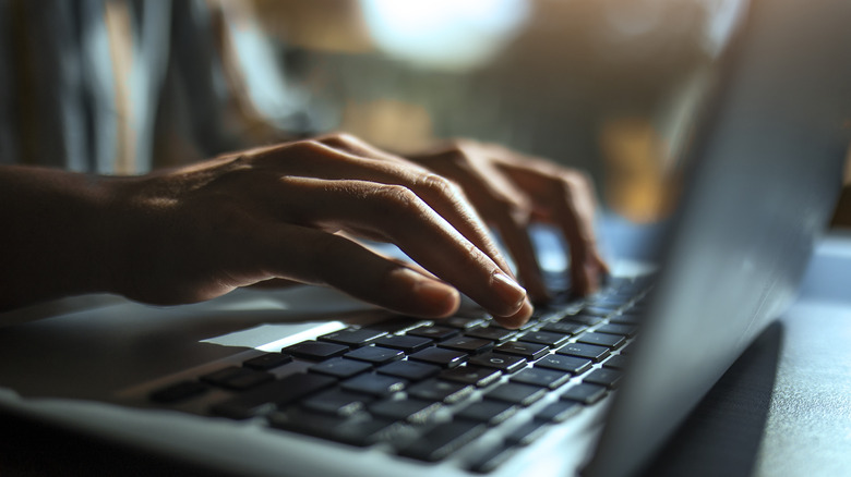 hands typing laptop keyboard