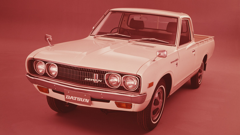Studio photo of a white 1972 Datsun Standard Body on red background