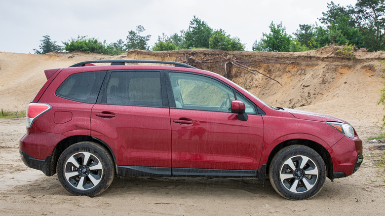 Red SUV Subaru Forester in a sand pit in the rain