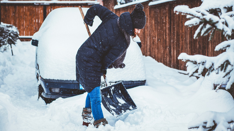 Woman shovelling car out of snow