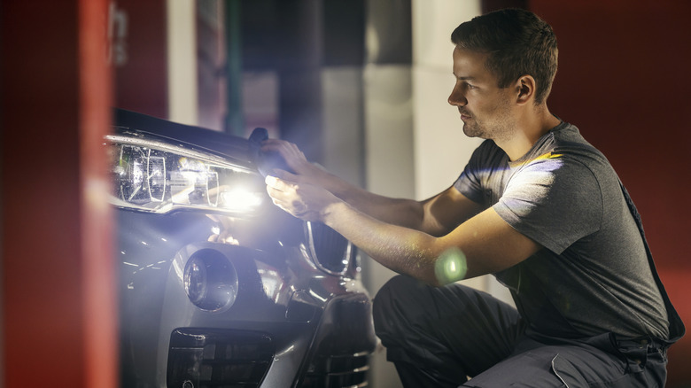 A person polishing bright headlights on a BMW SUV.