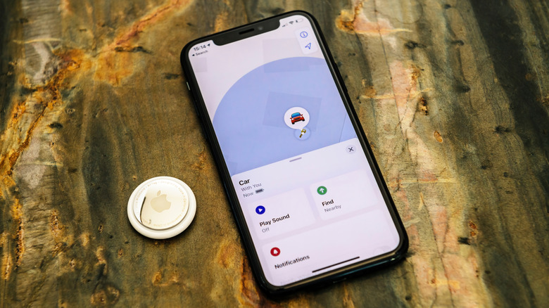 AirTag next to an iPhone on a wooden surface