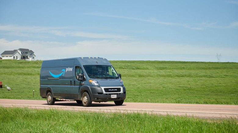 Amazon van on country road with grass field and white farmhouse behind
