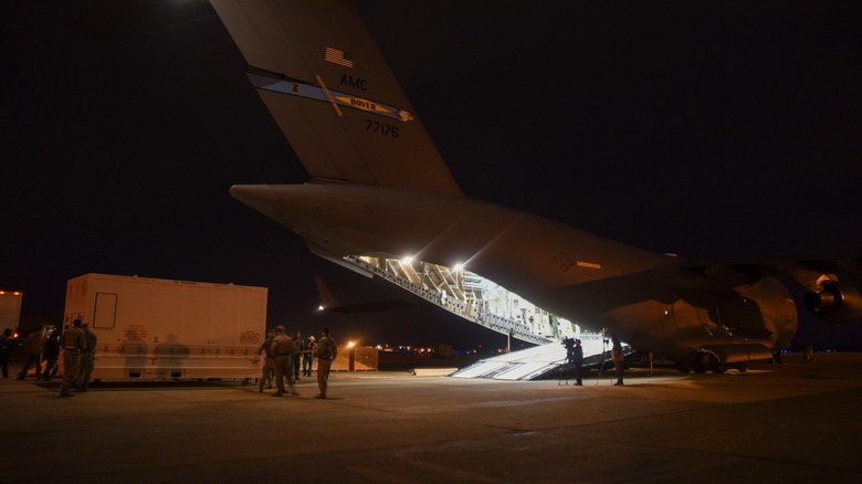 Airmen load containers onto a cargo plane at night.
