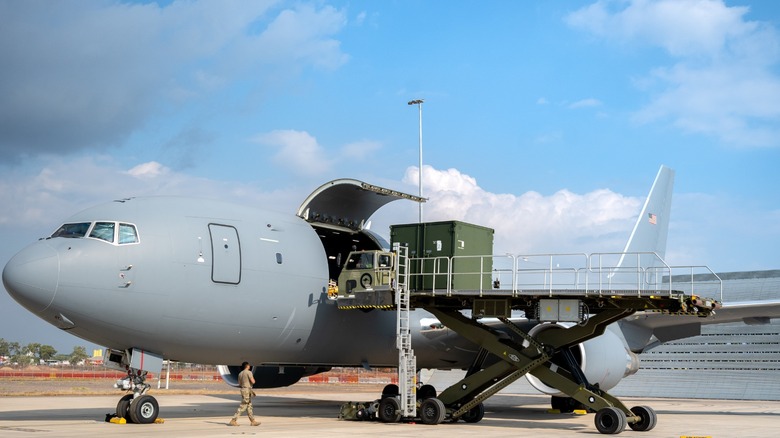 A KC-46 Pegasus being loaded with cargo from a side door.