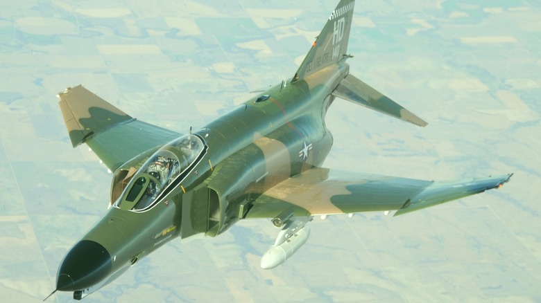 An F-4 Phantom II flying over pastoral land