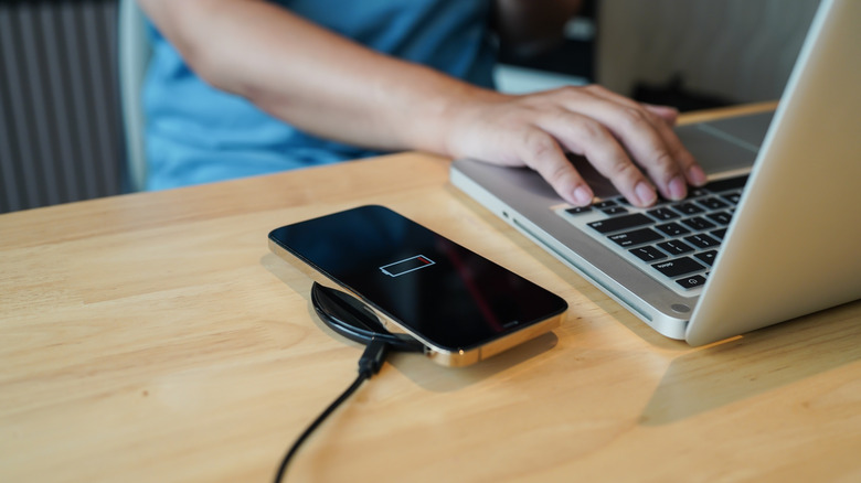 Phone charging wirelessly beside a laptop