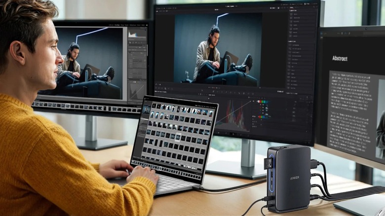 Man sitting at laptop with three monitors connected through docking station