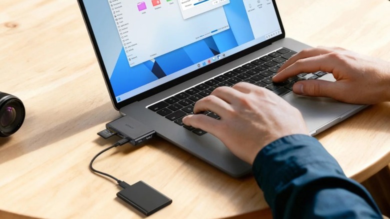 Man working on laptop with Anker removeable hub plugged in to laptop.