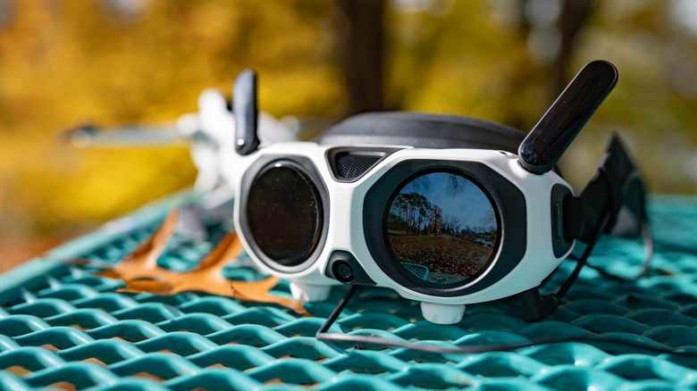 The Antigravity A1 goggles on a metal picnic table with the front display powered on and showing the view from the drone.