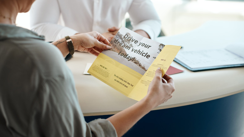 Woman looking at a pamphlet about buying her dream car