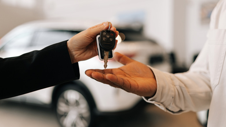 Car dealer hands keys to new car to customer