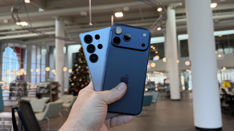 Man holding an iPhone 17 Pro Max and Samsung Galaxy S25 Ultra