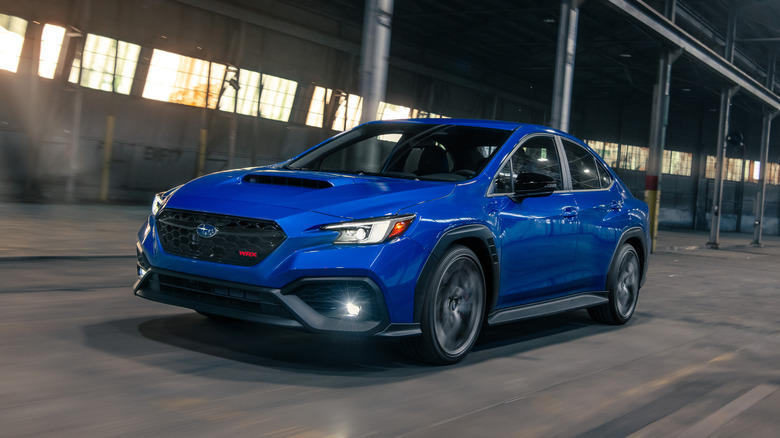 Front 3/4 view of 2025 Subaru WRX tS in blue, driving through a warehouse