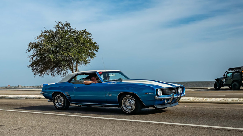 Classic 1969 Chevrolet Camaro driving on coastal road, front-right view