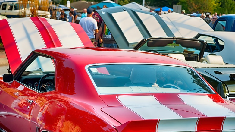 Rear view of a 1969 Camaro and Oldsmobile 442 at a car show with hoods open